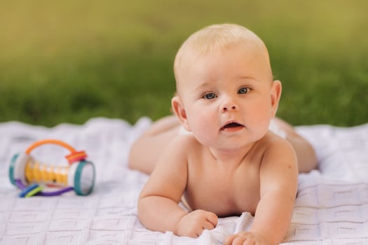 Cute happy toddler lying on a blanket on the grass outdoors in summer photo