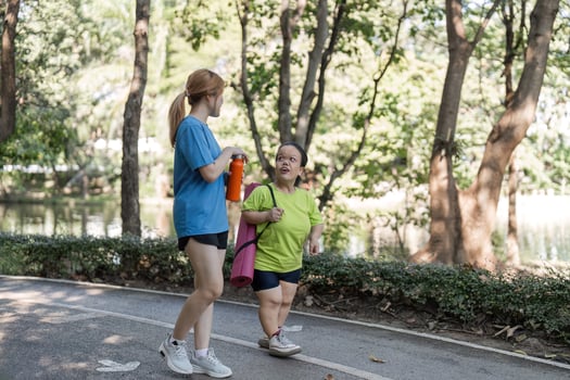 Petite Disabled Woman Exercising in the Park with Supportive Friend on a Sunny Day photo