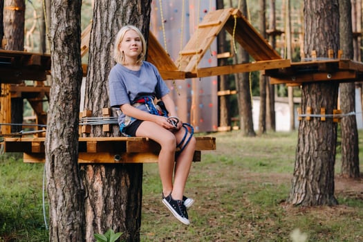 A girl passes an obstacle in a rope town. A girl in a forest rope park photo