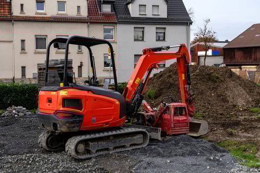 A red excavator and small digging machine work on a construction site photo