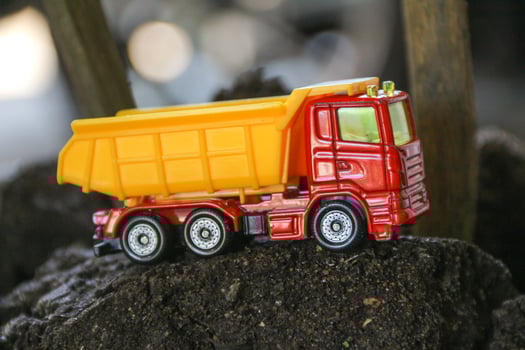 Children's toy colored small truck on the grass background of sand and stones loaded with cargo photo
