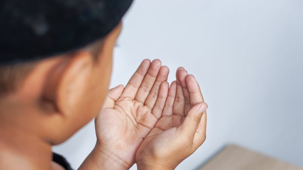 Hand of a praying muslim boy on a white background photo
