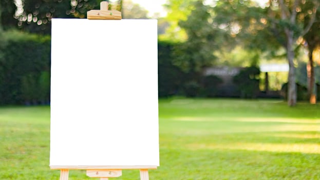 White board sign for writing text on blurred lush green trees background photo
