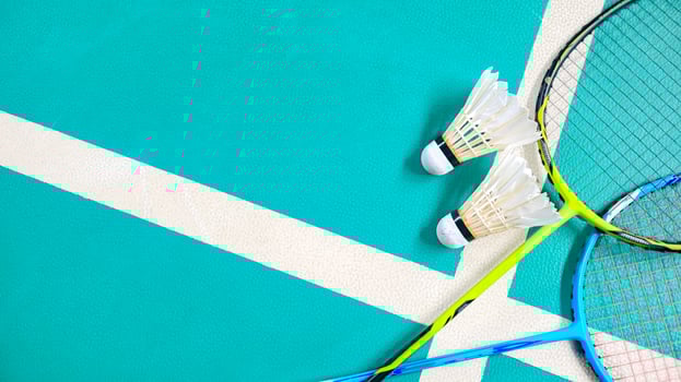 White badminton shuttlecocks and badminton rackets on green floor indoor badminton court. Concept for badminton competition and its lovers. photo
