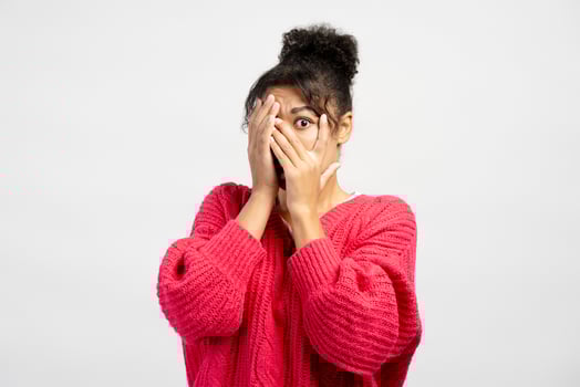 Scared young woman covering face with hands showing fear photo