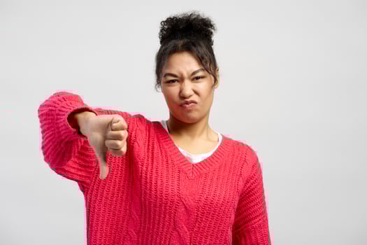 Young woman showing thumbs down gesture expressing dislike photo