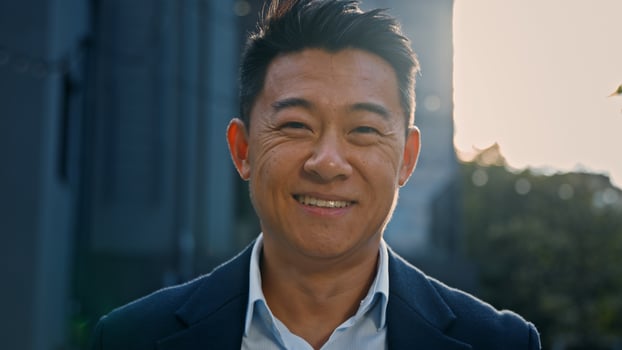 Outdoors portrait Asian 40s mature businessman smiling happy in city in sun lights. Close up glad success cheerful positive middle-aged man business CEO manager entrepreneur employer sunbeams sunset photo