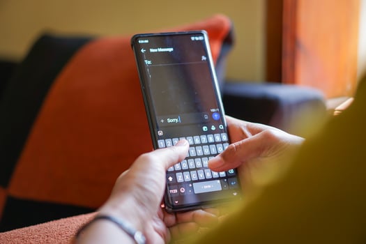 A person typing a sorry message on a smartphone, showcasing modern communication on a cozy couch. photo