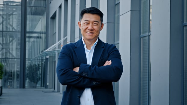 Smiling happy confident motivated successful 40s middle-aged Asian Korean man entrepreneur employer company CEO realtor businessman boss leader posing in downtown outdoors in city crossing hands smile photo