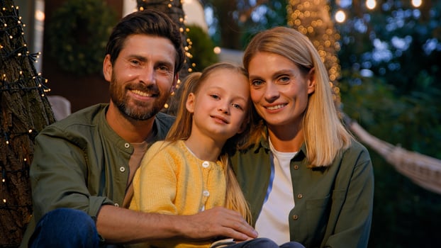 Family portrait happy Caucasian faces male female and kid woman bearded man and little girl father mother and child daughter outdoors smiling close up looking at camera in evening in camping backyard photo