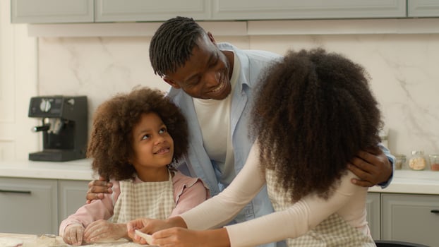 African American happy family at home kitchen mother with daughter cooking baking prepare cook flour dough cookie together lovely father hug child girl and wife hugging cuddling kid and mom culinary photo