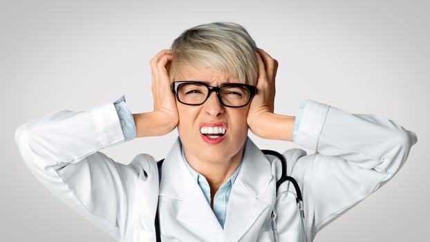 Headache from problems in medicine concept. Upset woman doctor holds her head with hands and closes eyes, panorama, free space photo