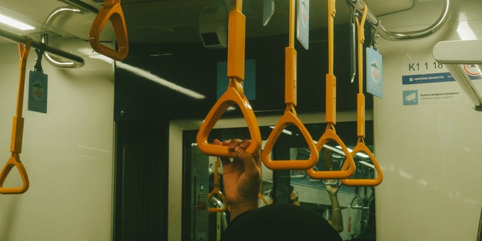 A person is holding onto a metal bar on a train photo