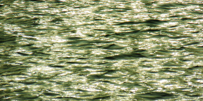 A close up of water with a reflection of the sun photo