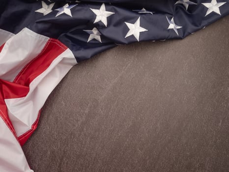 The American flag is on a black stone pattern background with copy space for text photo