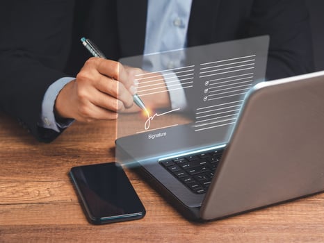Electronic signature. A businessman in a suit uses a pen to sign electronic documents on digital documents on a virtual screen photo