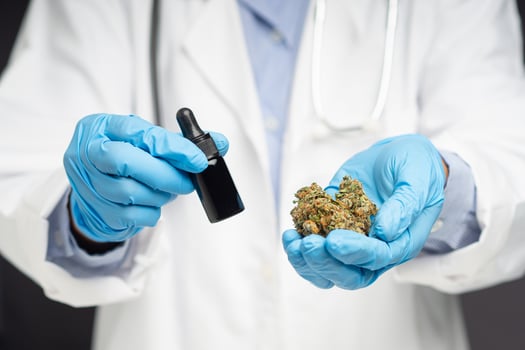 Doctor holding dry cannabis buds flower and cannabis oil bottle while standing in the medical science laboratory photo