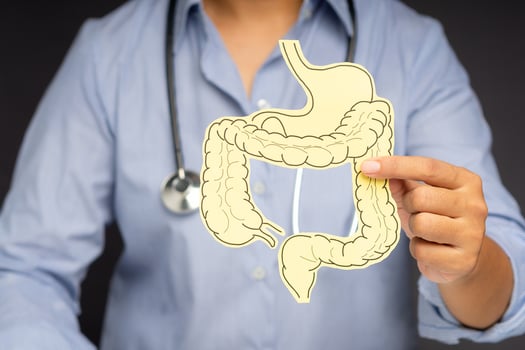 Hand of the doctor holding a colon symbol while standing on a gray background photo