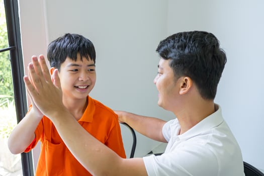 asian man and boy high five each other photo