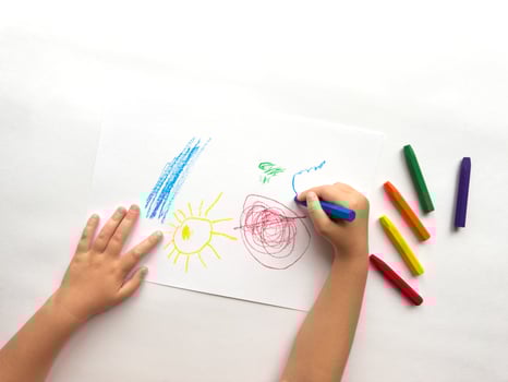 Childs hand drawing with colorful crayons on white paper. Creativity and imagination in action photo