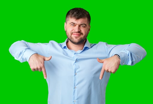 Man in a blue striped shirt and jeans gesturing downward against a bright green background photo
