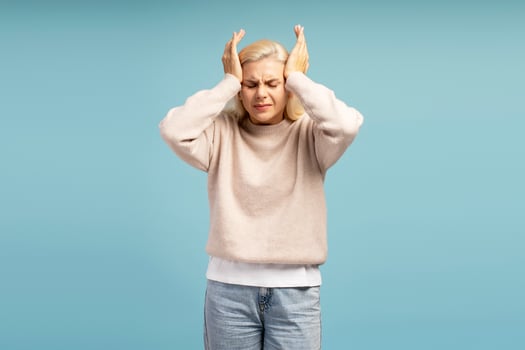 Stressed young woman suffering from headache touching temples on blue background photo