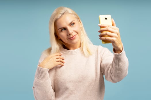 Smiling woman taking a selfie with smartphone on blue background photo