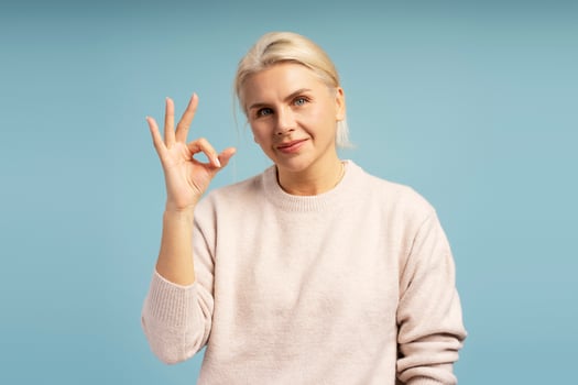Smiling woman gesturing ok sign on blue background photo