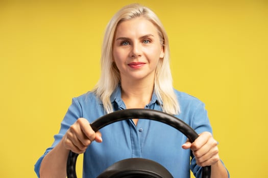 Businesswoman holding steering wheel on yellow background photo