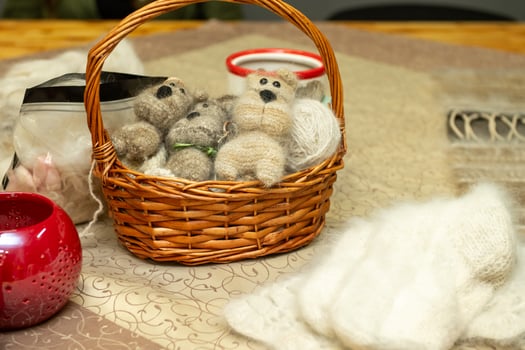 Wicker basket with handmade wool teddy bears and cozy decor on table photo