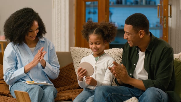 African American speech therapist mother father parents family child daughter learning talk pronounce word letter articulation support speak language praise achievement teamwork progress sound proud photo