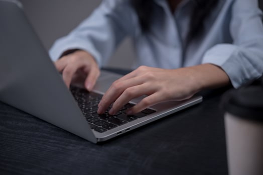 A woman typing on a laptop computer photo
