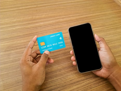 Hands Holding Credit Card and Smartphone on Wooden Table photo