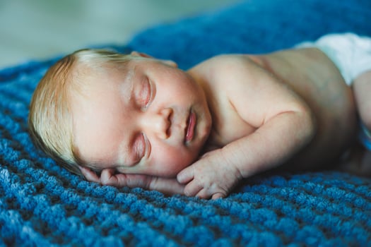 A newborn baby sleeps on a knitted blanket. A blanket made of natural fabric for a newborn baby. Baby sleep photo