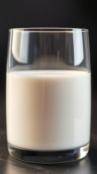 Close up of a glass filled with fresh milk against a dark background in a well-lit setting photo