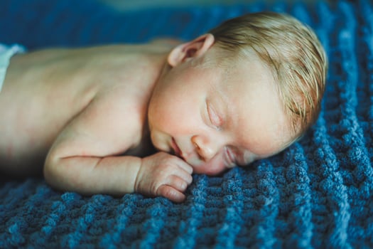 A newborn baby sleeps on a knitted blanket. A blanket made of natural fabric for a newborn baby. Baby sleep photo