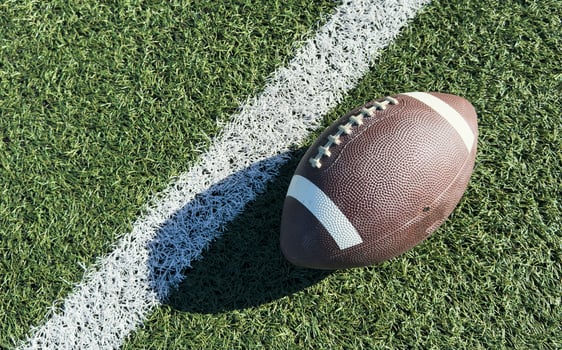 Close up of an american football on the field, players in the background photo