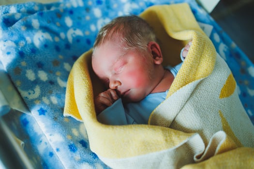 Newborn baby in blue romper. Photo of a newborn baby lying in a crib. The first photos of the baby.