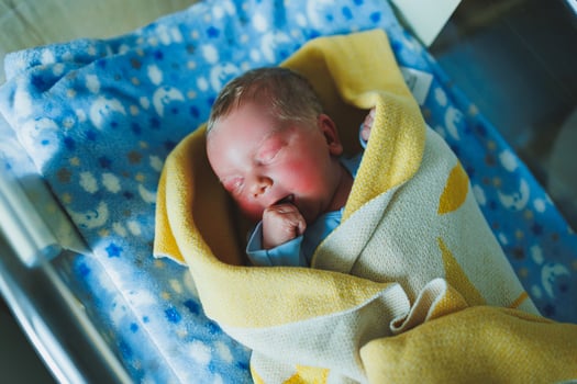 Newborn baby in blue romper. Photo of a newborn baby lying in a crib. The first photos of the baby.