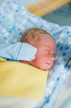 Newborn baby in blue romper. Photo of a newborn baby lying in a crib. The first photos of the baby.