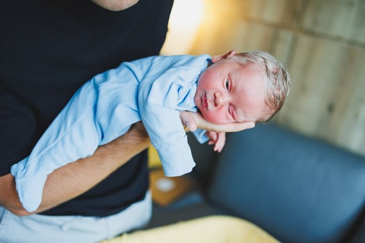 Newborn baby boy in his father's arms, lying on his arms close-up top view. A man is holding a small child. Healthy Lifestyle. Paternity photo