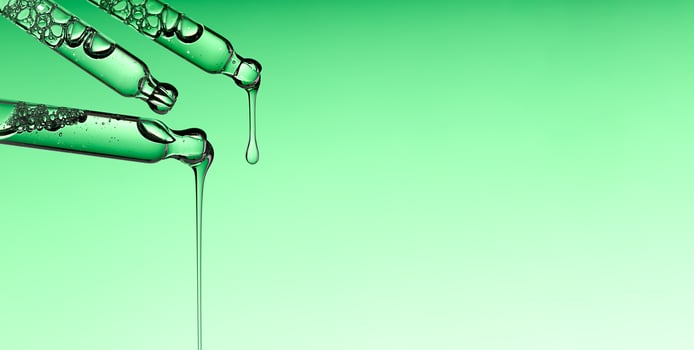 Pipette serum drop with niacinamide, hyaluronic or Aha Bha acids on a green isolated background photo