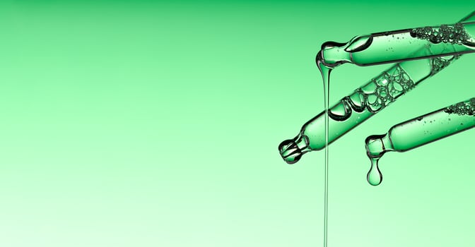 Pipette serum drop with niacinamide, hyaluronic or Aha Bha acids on a green isolated background. photo