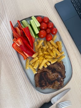 Grilled steak with colorful vegetables and pasta served on a wooden table photo