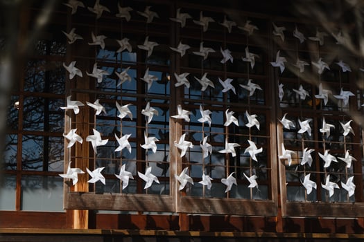 White paper pinwheels on wooden window in Japanese village. Concept of decoration, tradition, and peaceful cultural design photo