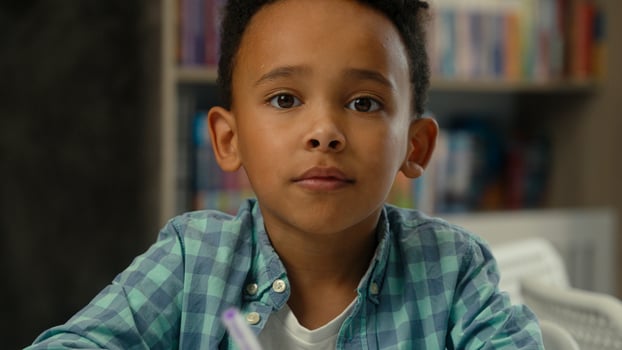 Little boy kid son African American ethnic child concentrated study learn write homework classroom lesson prepare task elementary school education student schoolboy studying drawing writing at desk photo