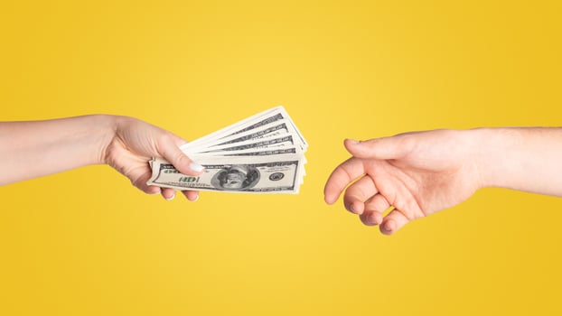 Close up of girl offering money to young guy against light background photo