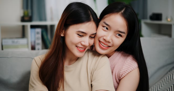 Portrait of Asian lesbian couple sit on the sofa, talk and hug happily, sharing good feelings with each other in the living room at home. LGBTQ Lifestyle. photo