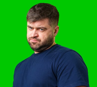 Man expressing confusion with crossed arms in front of a bright green background photo