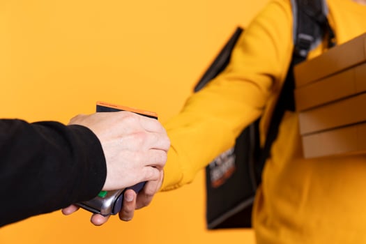 Customer paying with credit card to part time delivery worker holding takeaway order. Close up shot of customer buying meal from courier, swiping card on POS device, studio background photo